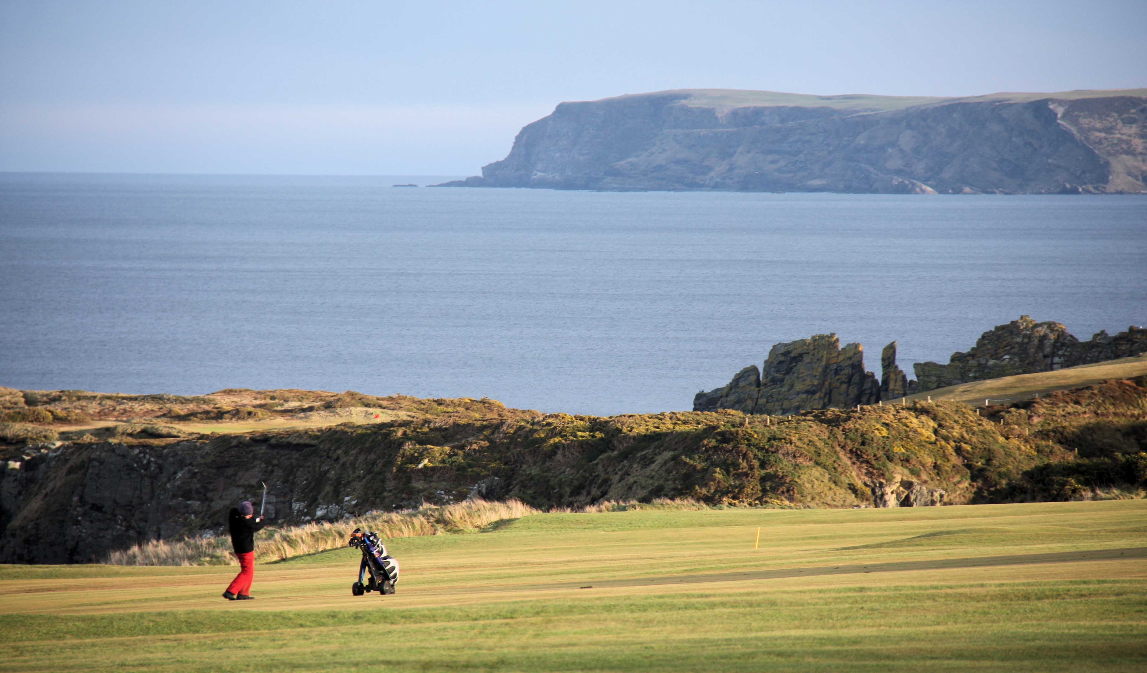 En golfer ved kysten med klipper I bakgrunnen, Aberdeen. 
