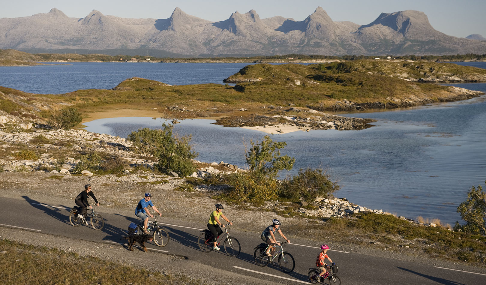 Syklister med fjellrekken De syv søstre i bakgrunnen i Helgeland i Nordland. 