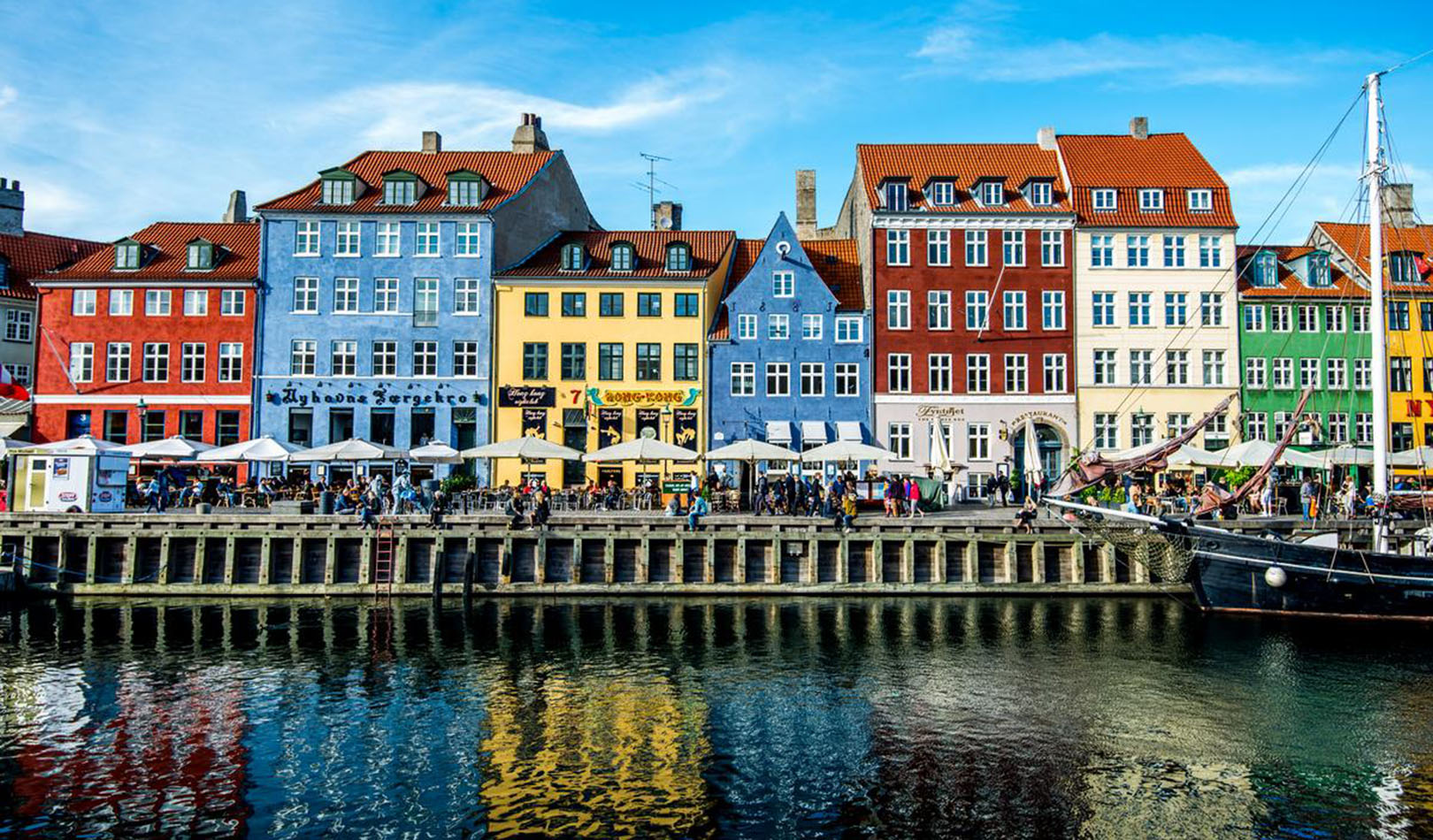 Colorful houses in Nyhavn with people in enjoying themselves in restaurants. 