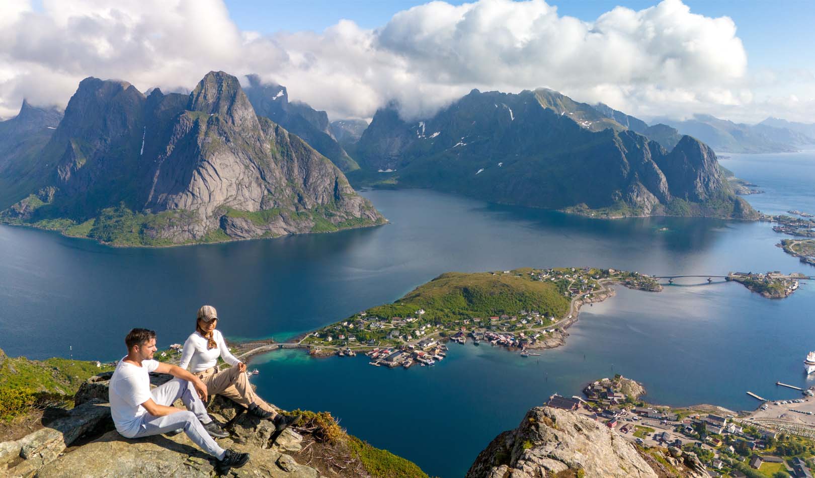 Hikers enjoying the view from the top of Reinebringen in Lofoten.