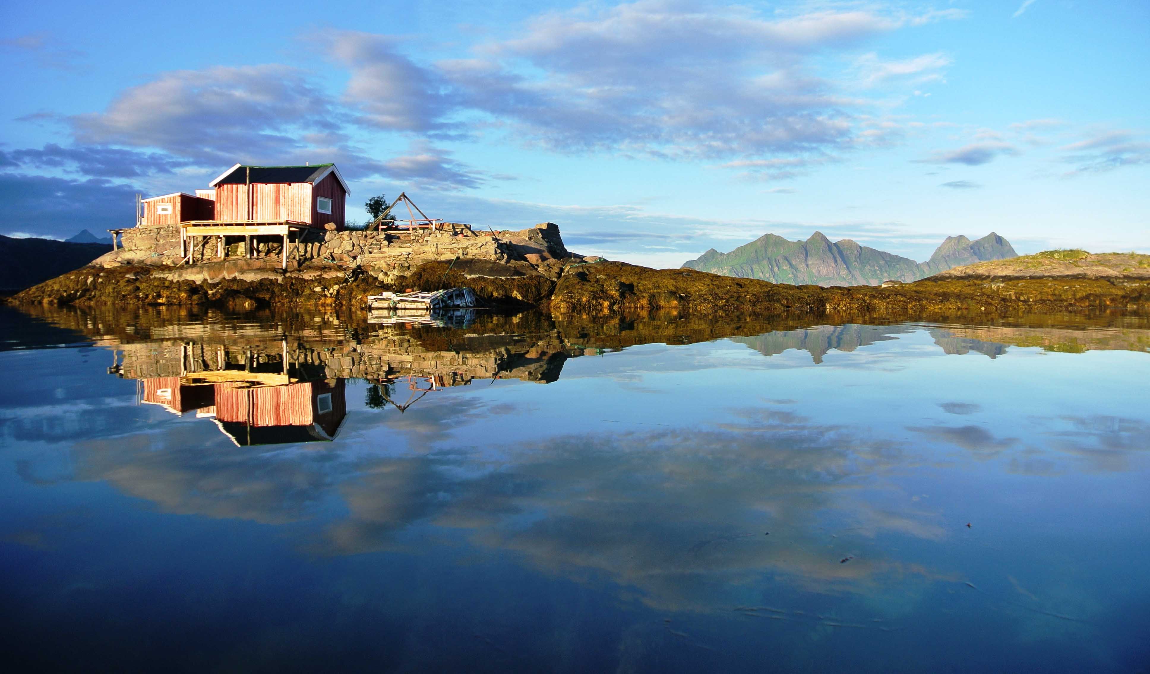 Sjøhus og fjell i vannspeil utenfor Svolvær, Lofoten.