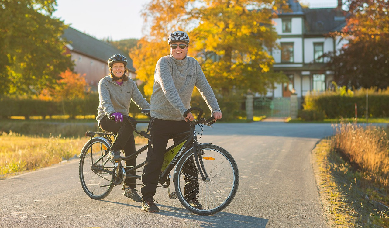Par på tandemsykkel i høstfarger utenfor Vinje bruk i Mosvik, Trøndelag. Couple on a tandem bike surrounded by autumn colors in Mosvik, Trøndelag.