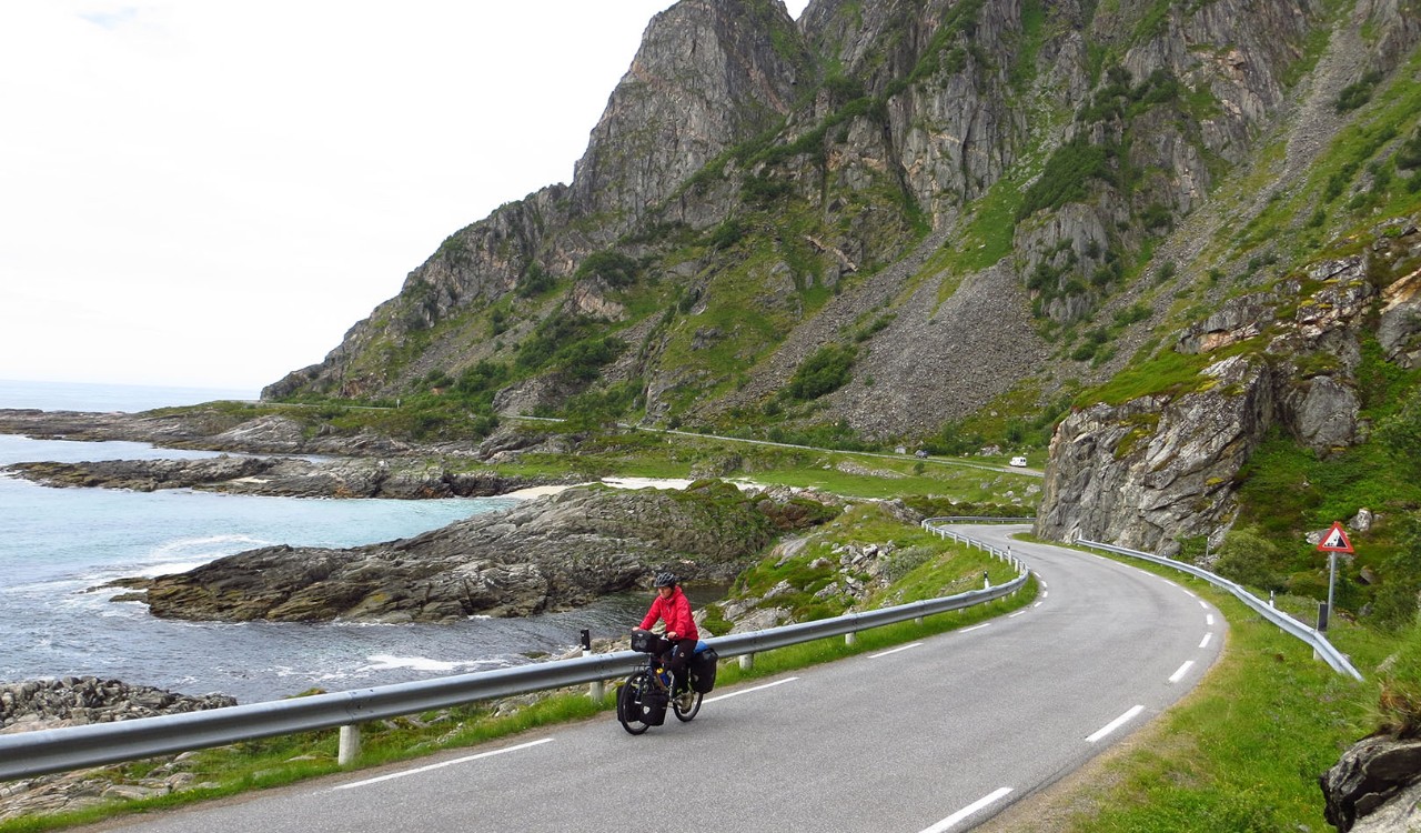 Kvinne på sykkeltur ved Bleik på Andøya i Vesterålen. Woman biking by the mountains and the village of Bleik, Andøya, Vesterålen.