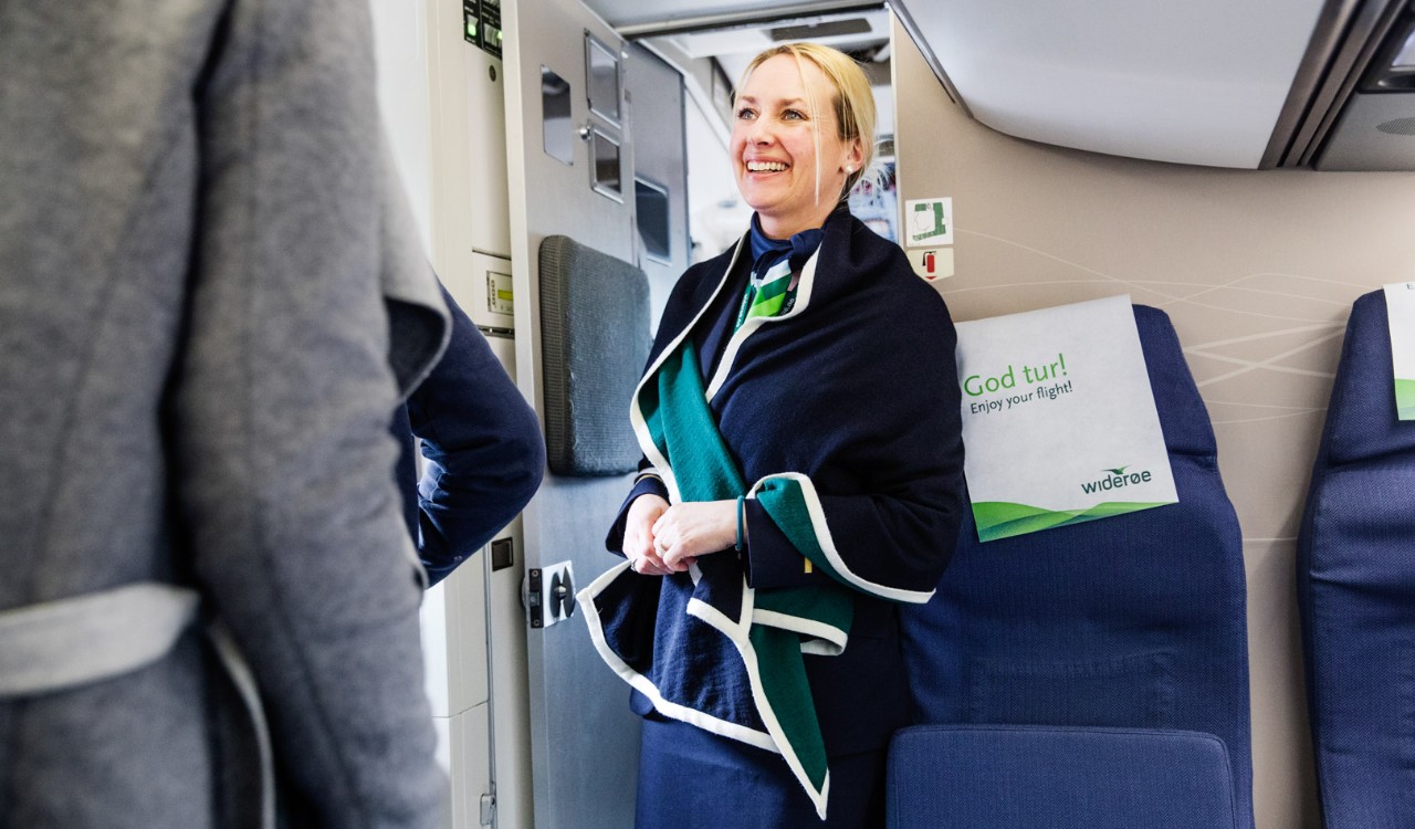 Kabinansatt Hanne Meland Hemminghytt snakker med passasjerer. Widerøe employee Hanne Meland Hemminghytt talking to passengers.