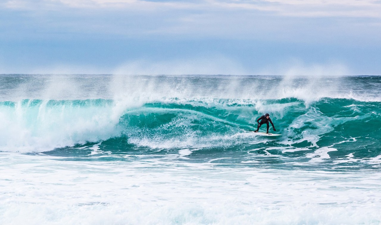 Mann surfer på bølge ved Unstad, Lofoten. Man surfing on wave in Unstad, Lofoten.