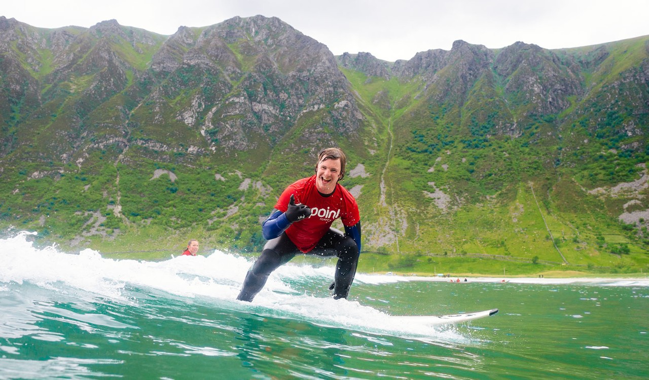 Mann surfer på med fjell i bakgrunnen. Man surfing with mountain in the background.