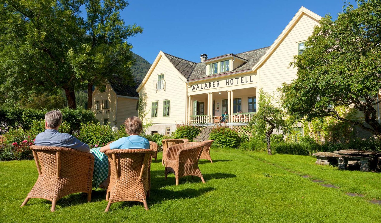 Par sitter i hagen ved gamle Walaker Hotell i Solvorn. Couple sitting in the garden of old Walaker Hotel in Solvorn.
