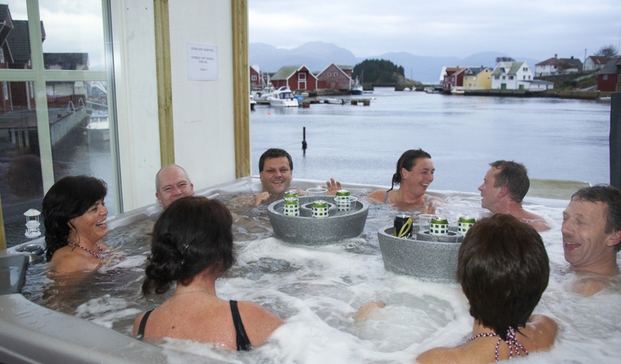 Folk i boblebad med utsikt til sjø og hus. People enjoying the jacuzzi with view of the sea and houses. 