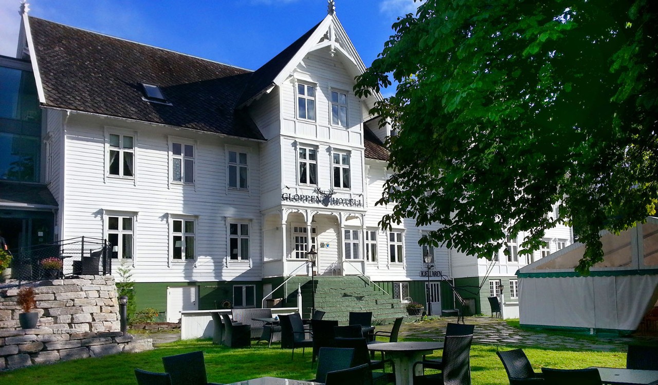 Fasaden på Gloppen Hotell, gammel, hvit trebygning. The exterior of Gloppen Hotell, and old, white, charming building. 