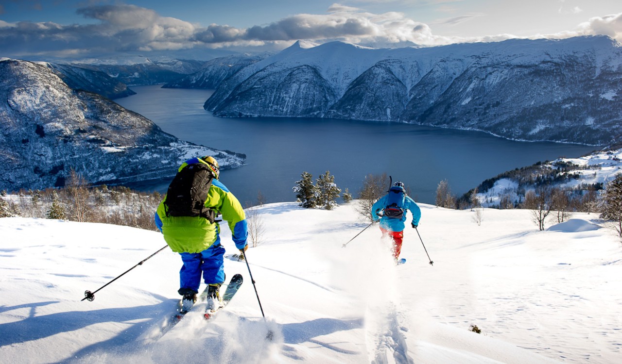To skiløpere setter utfor på fjellet i Sogndal. Two skiers skiing downhill in Sogndal.