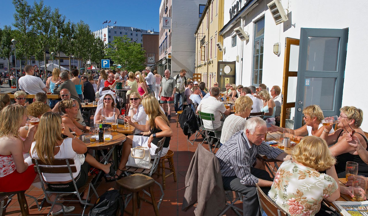 Folk nyter en sommerdag på uteserveringen til restauranten Skarven I Tromsø. People enjoying a summer day at the outdoor terrace of the restaurant Skarven in Tromsø.