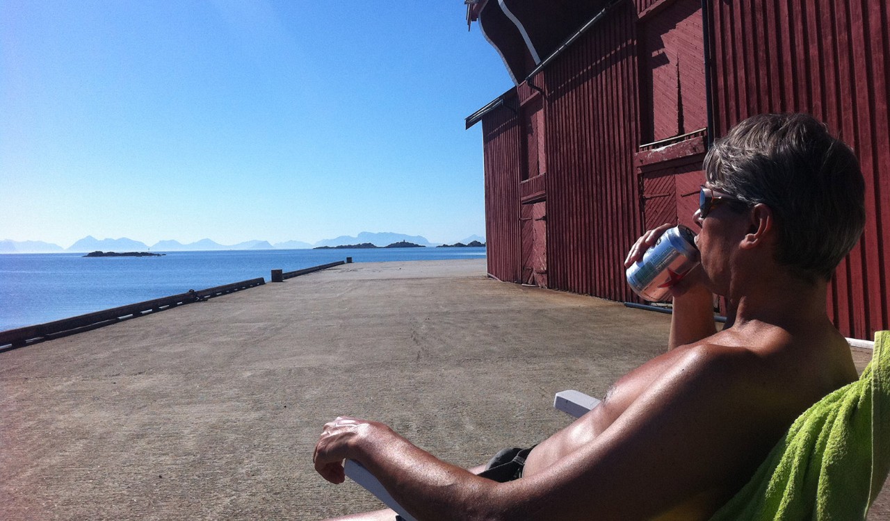 Mann drikker øl på brygga Skagakaia ved Vinje i Bø i Vesterålen. Man having a beer at the docks of Skagakaia in the municipality of Bø in Vesterålen.