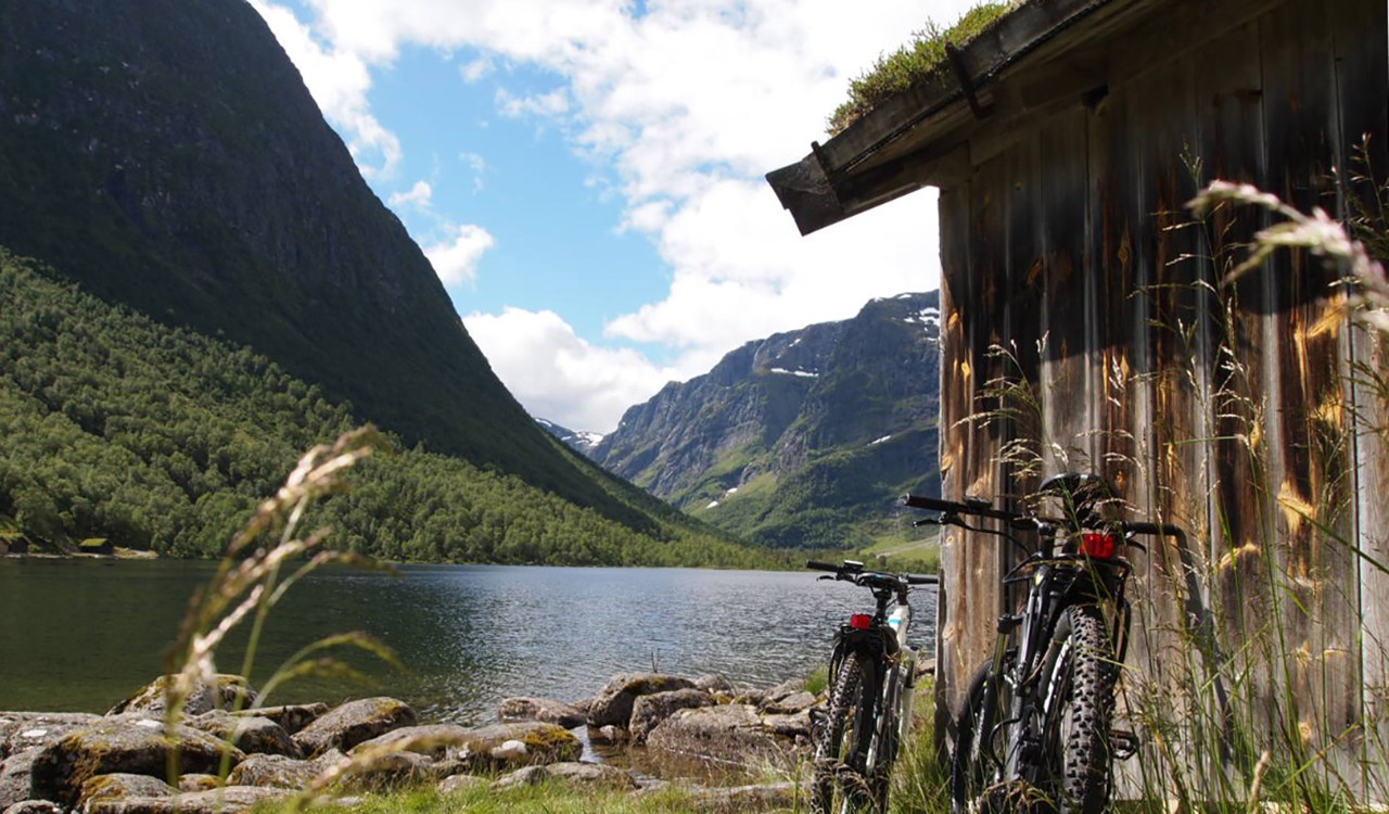 To sykler utenfor et naust ved fjorden, Sandane. Bikes on the side of a boat house by the fjord, Sandane.