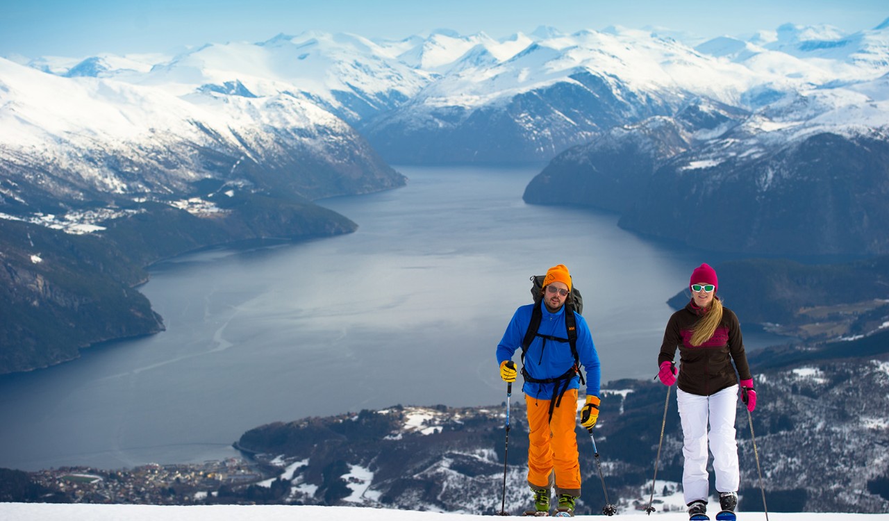 To skiløpere på vei oppover Strandafjellet. Two skiers walking on Strandafjellet, with mountains and fjords in then background.