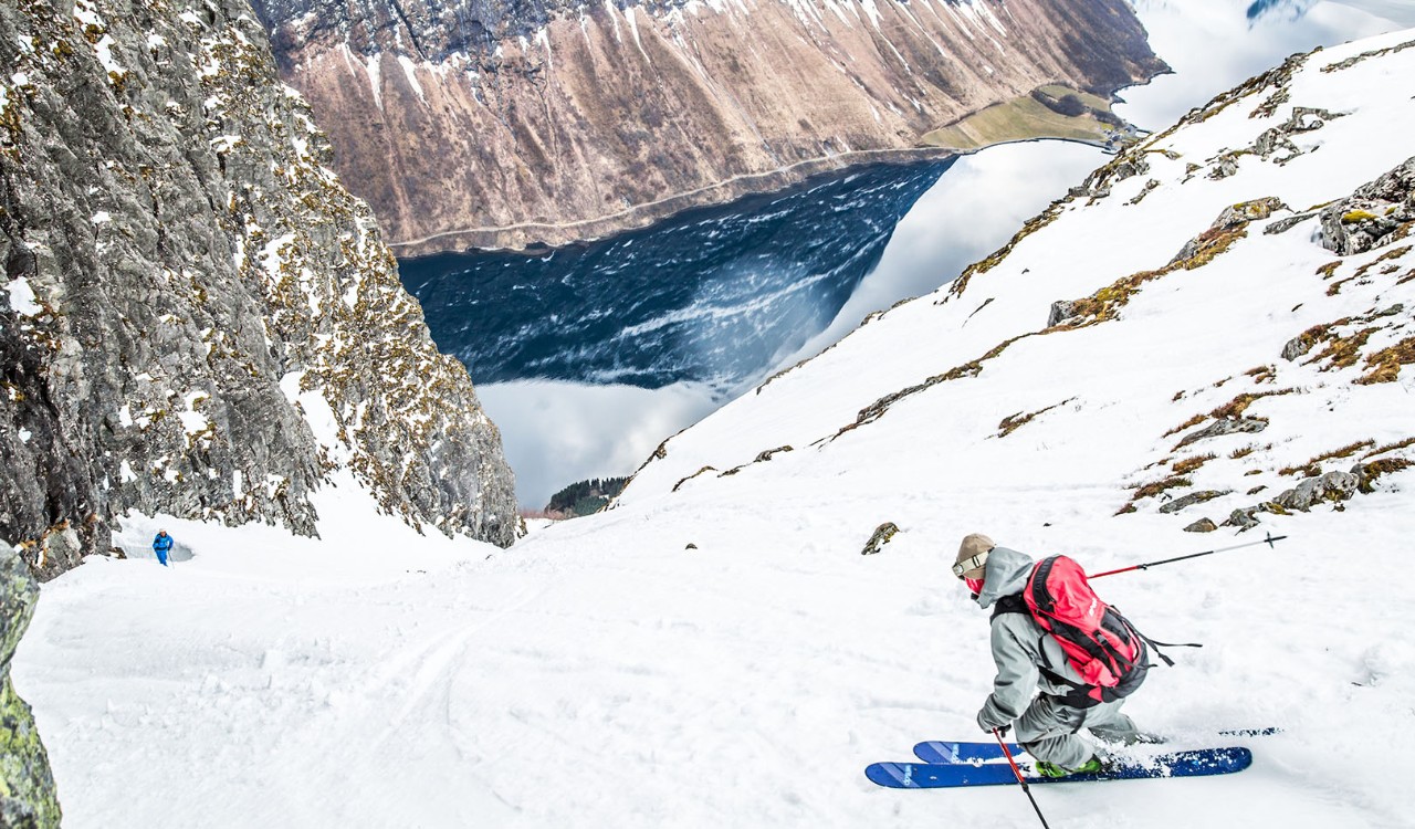 Skiløper nedover bratt fjellside mot Norangsfjorden. Skier steep downhill towards Norangsfjorden.