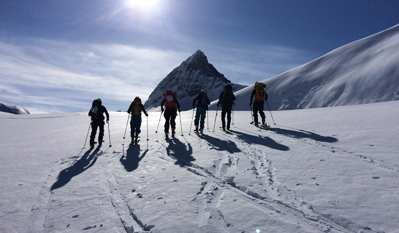 Seks skiløpere på vei oppover fjellet, Hjørundfjorden; Møre og Romsdal. Six skiers walking up a snowy mountainside, Hjørundfjorden, Møre og Romsdal