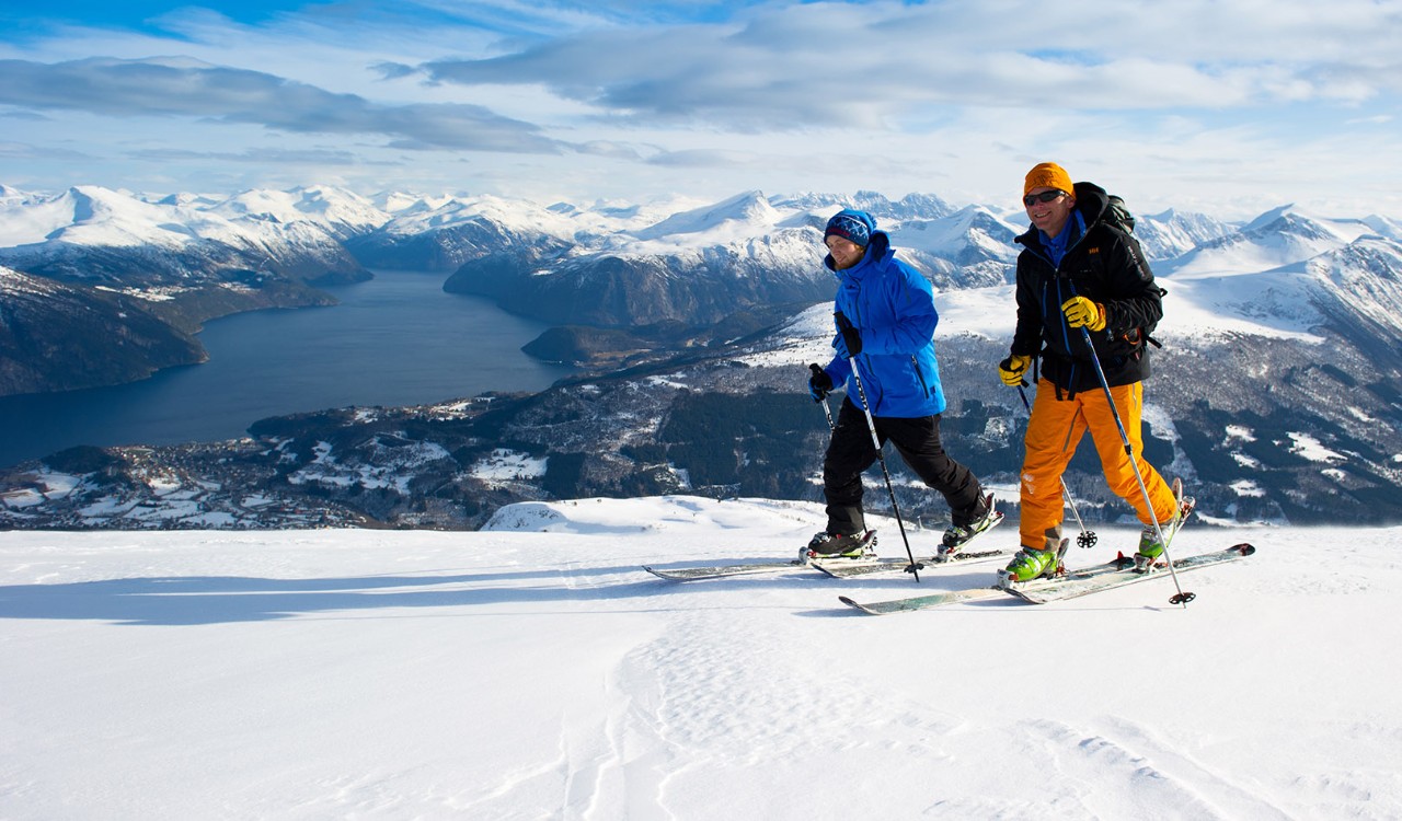 To skiløpere på Strandafjellet med fjell og fjord i bakgrunnen. Skiers on Strandfjellet with mountains and fjords in the background.